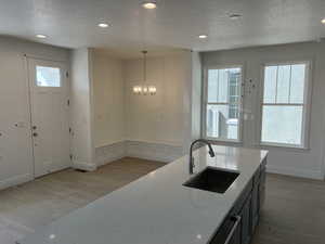 Kitchen with light wood-style floors, a sink, light stone countertops, and a wealth of natural light
