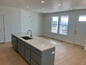 Kitchen featuring dishwasher, a sink, light wood-style floors, recessed lighting, and gray cabinets