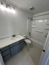 Bathroom with washtub / shower combination, vanity, a textured ceiling, toilet, and visible vents