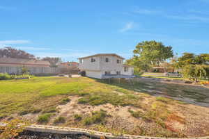 Rear view of property featuring a trampoline, garden area, and rear open patio