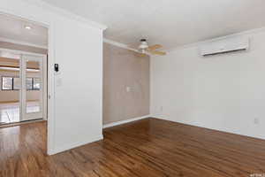 Spare room with dark wood-type flooring, a wall mounted AC, crown molding, and ceiling fan