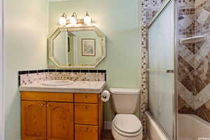 Full bathroom featuring vanity, toilet, tasteful backsplash, and enclosed tub / shower combo