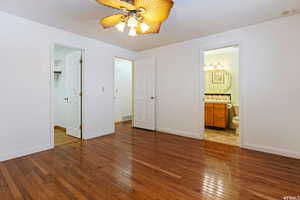 Unfurnished bedroom featuring connected bathroom, ceiling fan, and dark wood-type flooring