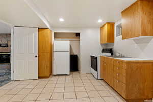 Kitchen featuring white appliances, light tile patterned floors, and sink