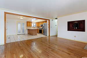 Unfurnished living room with french doors, ornamental molding, a textured ceiling, and light wood-type flooring