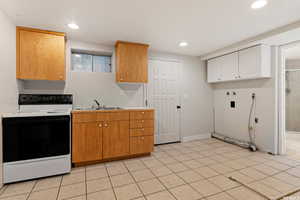 Kitchen with sink, white cabinetry, light tile patterned floors, and white electric stove