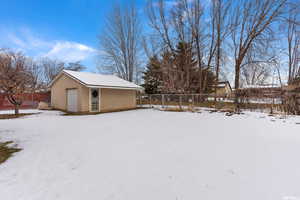 Yard covered in snow with a garage and an outbuilding