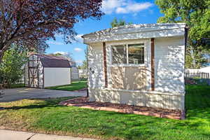 View of side of property with a yard and a shed