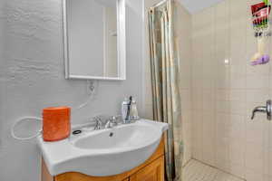 Bathroom with vanity, curtained shower, and tile patterned flooring