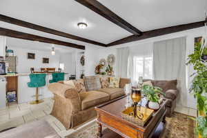 Tiled living room featuring lofted ceiling with beams