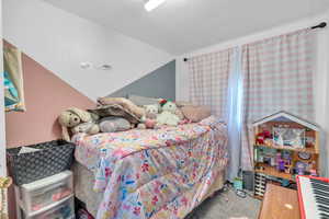 Carpeted bedroom featuring vaulted ceiling