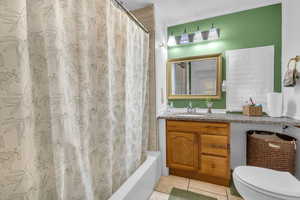 Full bathroom featuring toilet, tile patterned flooring, vanity, and shower / tub combo