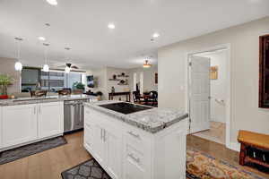 Kitchen featuring black electric stovetop, sink, light hardwood / wood-style floors, stainless steel dishwasher, and white cabinets