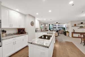 Kitchen with appliances with stainless steel finishes, sink, kitchen peninsula, hanging light fixtures, and white cabinetry.