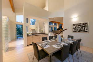 Dining area featuring light hardwood / wood-style flooring, beam ceiling, and a high ceiling