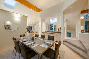 Dining area with light hardwood / wood-style floors and vaulted ceiling with beams