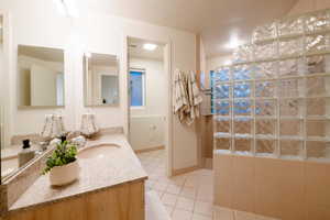 Bathroom with vanity, a shower, and tile patterned floors