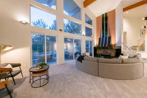 Carpeted living room with beam ceiling and high vaulted ceiling