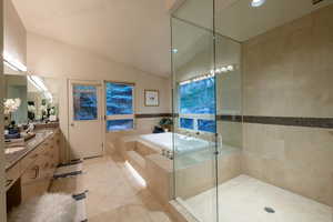 Bathroom featuring lofted ceiling, tile walls, vanity, plus walk in shower, and tile patterned floors