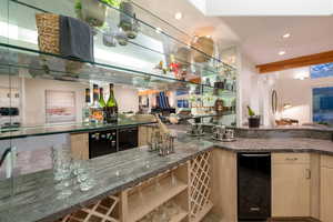 Bar featuring black dishwasher and stone countertops