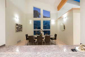 Tiled dining space with vaulted ceiling with beams