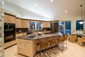 Kitchen with tasteful backsplash, sink, an island with sink, stainless steel appliances, and lofted ceiling