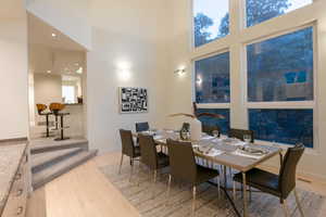 Dining room with light hardwood / wood-style flooring and a towering ceiling