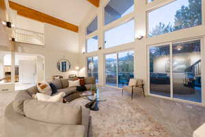 Carpeted living room featuring beam ceiling and high vaulted ceiling