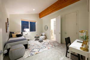 Carpeted bedroom featuring ensuite bathroom and vaulted ceiling with beams