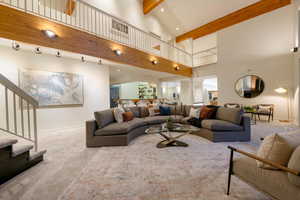 Carpeted living room featuring beam ceiling and high vaulted ceiling