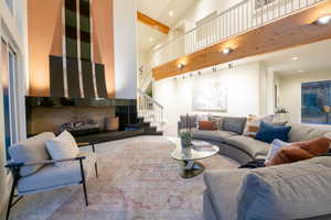 Living room with beam ceiling, high vaulted ceiling, and carpet