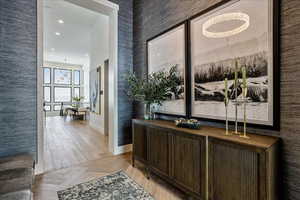 Hall featuring light parquet flooring and an inviting chandelier