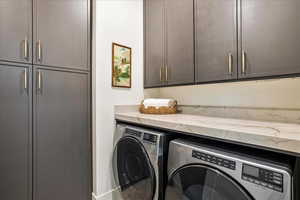 Washroom featuring washing machine and dryer and cabinets