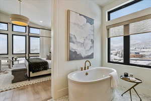 Bathroom with hardwood / wood-style floors, lofted ceiling, plenty of natural light, and a bathing tub