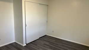 Unfurnished bedroom featuring a closet and dark wood-type flooring