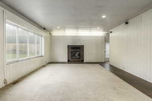 Unfurnished living room with a tile fireplace, carpet floors, and wooden walls