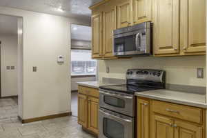 Kitchen featuring a textured ceiling and stainless steel appliances