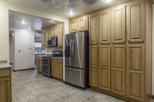 Kitchen featuring a textured ceiling and appliances with stainless steel finishes