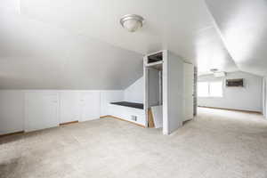 Bonus room with a wall mounted air conditioner, light carpet, and lofted ceiling