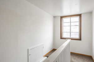 Hallway featuring light colored carpet