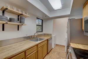 Kitchen featuring stainless steel appliances, sink, butcher block counters, and washer / dryer