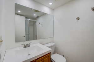 Bathroom with vanity, a shower with shower door, and toilet