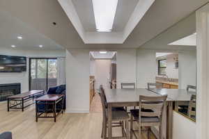 Dining area with a brick fireplace, light wood-type flooring, sink, and a healthy amount of sunlight