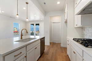 Kitchen featuring sink, stainless steel appliances, a gas range, pendant lighting, white cabinets, and custom range hood