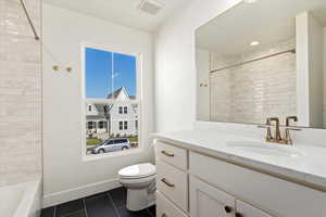 Full bathroom with toilet, tiled shower / bath, vanity, and tile patterned flooring