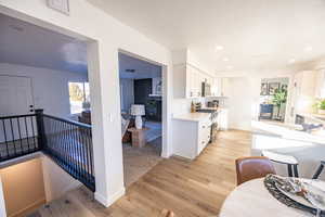 Kitchen with light hardwood / wood-style flooring, white cabinets, and stainless steel appliances