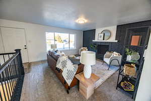 Living room with carpet flooring, a fireplace, and a textured ceiling