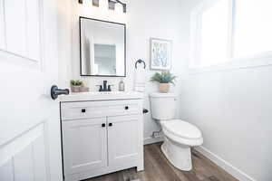 Bathroom with hardwood / wood-style floors, vanity, and toilet