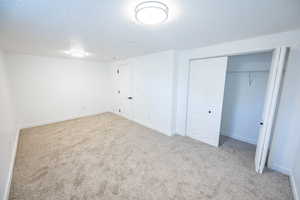 Unfurnished bedroom with a closet, light colored carpet, and a textured ceiling