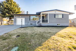 Single story home featuring covered porch, a garage, and a front yard